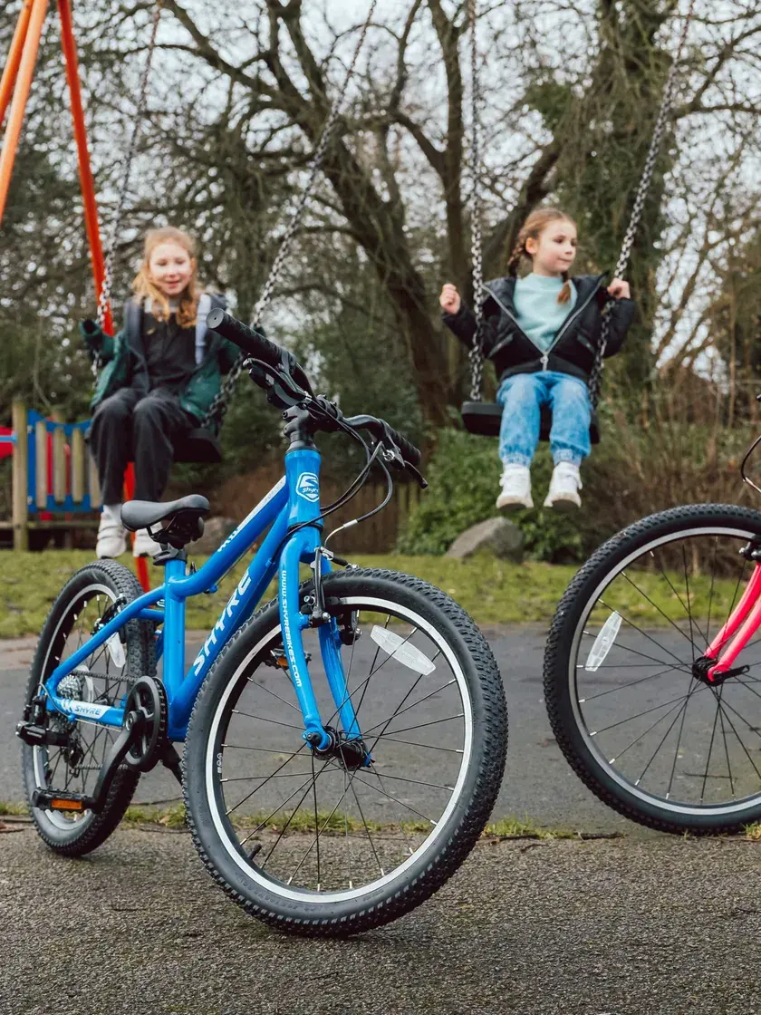 Shyre bikes at the park while the kids play